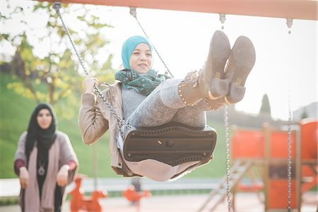 sitting in jeans - Two young women playing on playground swings Stock Photo - Premium Royalty-Free, Code: 649-08086852