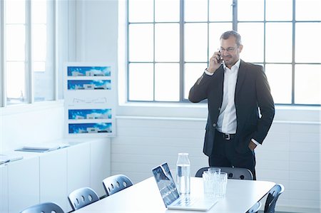 Business man chatting on smartphone in conference room Stock Photo - Premium Royalty-Free, Code: 649-08117873