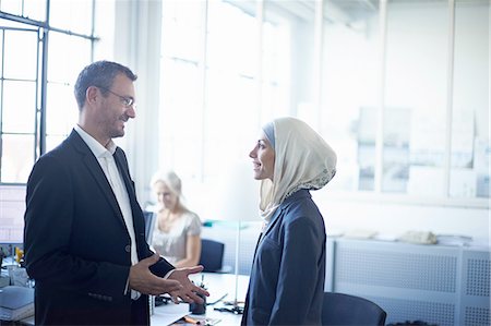 religion - Mature businessman talking to young businesswoman in office Stock Photo - Premium Royalty-Free, Code: 649-08117897