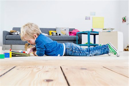 Boy playing with digital tablet on wooden floor Stock Photo - Premium Royalty-Free, Code: 649-08118136