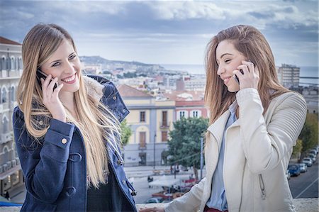 simsearch:649-07736862,k - Two young women on rooftop talking on smartphones, Cagliari, Sardinia, Italy Stock Photo - Premium Royalty-Free, Code: 649-08118444