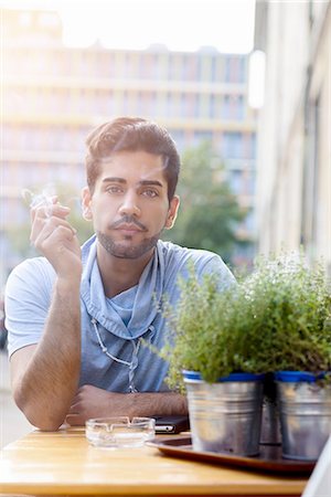 simsearch:614-08392638,k - Portrait of young man outdoors, sitting at table, smoking cigarette Foto de stock - Sin royalties Premium, Código: 649-08118637