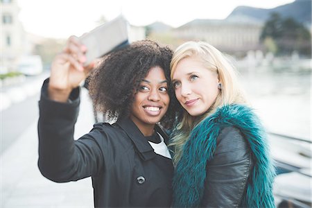 Two young women posing for smartphone selfie at Lake Como, Como, Italy Stock Photo - Premium Royalty-Free, Code: 649-08118794