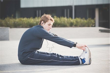 Young man touching toes in city square Stock Photo - Premium Royalty-Free, Code: 649-08118836