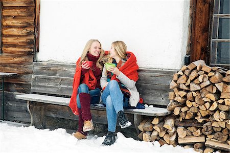 friends talking outside - Two young female friends drinking coffee outside wooden cabin Stock Photo - Premium Royalty-Free, Code: 649-08124900