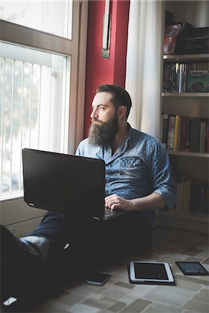 Young bearded man using laptop on floor Stock Photo - Premium Royalty-Free, Code: 649-08125269