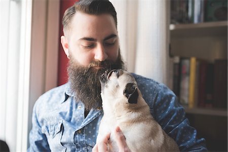 Young bearded man carrying dog in arms Stock Photo - Premium Royalty-Free, Code: 649-08125272