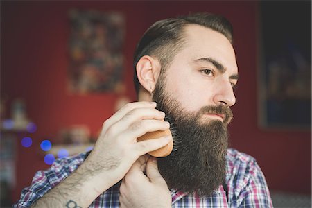 Young bearded man brushing his beard Stock Photo - Premium Royalty-Free, Code: 649-08125290