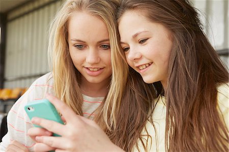 simsearch:649-07804673,k - Two girls reading smartphone texts in shelter Photographie de stock - Premium Libres de Droits, Code: 649-08125589