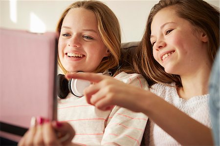 simsearch:614-06442812,k - Two girls on sofa laughing and pointing at digital tablet Stock Photo - Premium Royalty-Free, Code: 649-08125625
