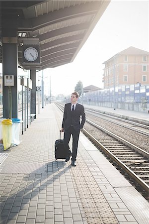 railway station with people - Portrait of young businessman commuter walking along railway platform. Stock Photo - Premium Royalty-Free, Code: 649-08144807