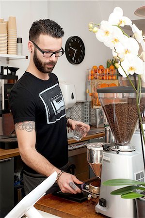 Cafe waiter preparing fresh coffee using machine behind counter Stock Photo - Premium Royalty-Free, Code: 649-08145015