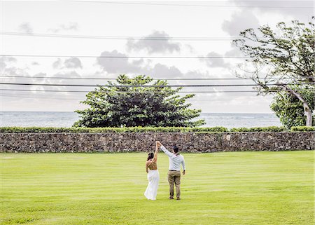 Rear view of bride and bridegroom holding raised hands in garden at Hawaiian wedding, Kaaawa, Oahu, Hawaii, USA Stock Photo - Premium Royalty-Free, Code: 649-08145059