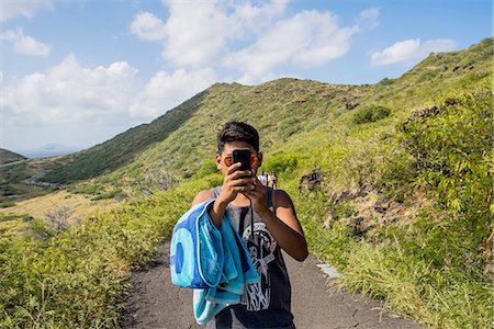 Portrait of young man taking smartphone selfie on Makapuu coast path, Oahu, Hawaii, USA Stock Photo - Premium Royalty-Free, Code: 649-08145076