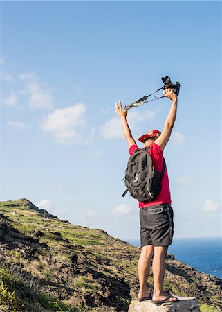 Young male tourist holding up his digital SLR on Makapuu coast path, Oahu, Hawaii, USA Stock Photo - Premium Royalty-Free, Code: 649-08145082