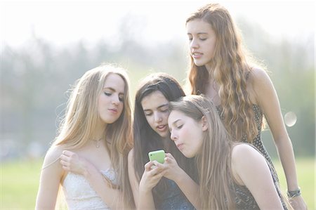 simsearch:649-07804673,k - Four teenage girls reading smartphone texts in park Photographie de stock - Premium Libres de Droits, Code: 649-08145154