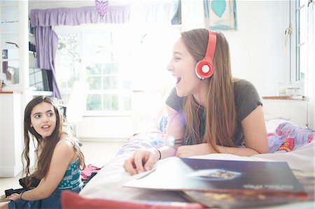 simsearch:649-07648247,k - Teenage girl chatting to friend whilst listening to headphones in bedroom Stock Photo - Premium Royalty-Free, Code: 649-08145190