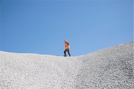 Quarry worker chatting on smartphone on top of quarry gravel mound Stock Photo - Premium Royalty-Free, Code: 649-08145202