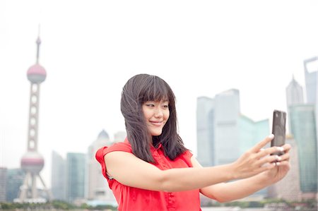 Young woman looking at smartphone, outdoors, Shanghai, China Stock Photo - Premium Royalty-Free, Code: 649-08145355