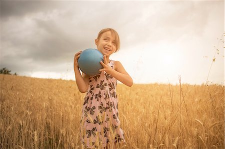 Girl holding blue ball in wheat field Stock Photo - Premium Royalty-Free, Code: 649-08179892