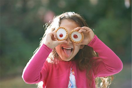 female sticking tongue out - Portrait of girl with tartlets in front of her eyes in garden Stock Photo - Premium Royalty-Free, Code: 649-08238506