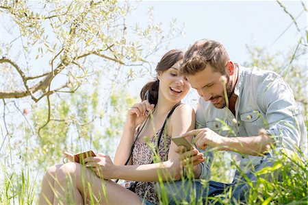 simsearch:649-08239088,k - Low angle view of young couple sitting looking down at smartphone smiling Stock Photo - Premium Royalty-Free, Code: 649-08239096