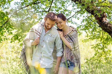 simsearch:649-08239088,k - Young couple walking wrapped in blanket looking down smiling Stock Photo - Premium Royalty-Free, Code: 649-08239097