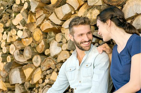 simsearch:649-08239088,k - Young couple sitting in front of chopped wood face to face smiling Stock Photo - Premium Royalty-Free, Code: 649-08239102