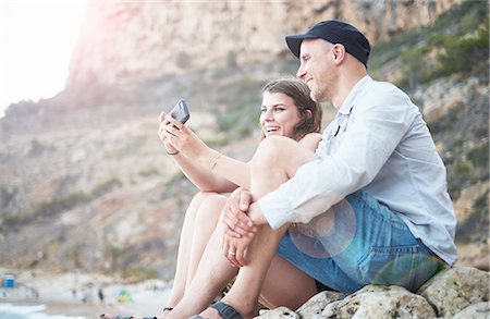 Mature man and teenage daughter reading smartphone texts on rocky beach, Javea, Spain Stock Photo - Premium Royalty-Free, Code: 649-08232688