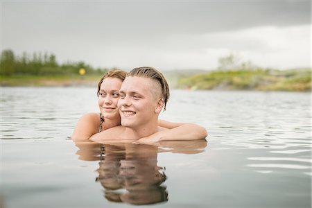 Young couple looking sideways from Secret Lagoon hot spring (Gamla Laugin), Fludir, Iceland Stock Photo - Premium Royalty-Free, Code: 649-08232736