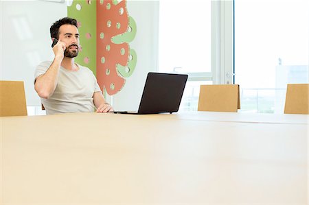 simsearch:649-06845199,k - Young male designer talking on smartphone at boardroom table Stock Photo - Premium Royalty-Free, Code: 649-08306337