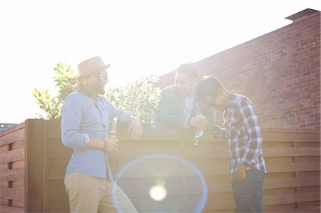 Three male friends chatting and drinking beer at rooftop party Stock Photo - Premium Royalty-Free, Code: 649-08306638