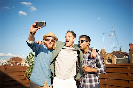 Three male friends taking camera selfie at rooftop party Foto de stock - Sin royalties Premium, Código: 649-08306640