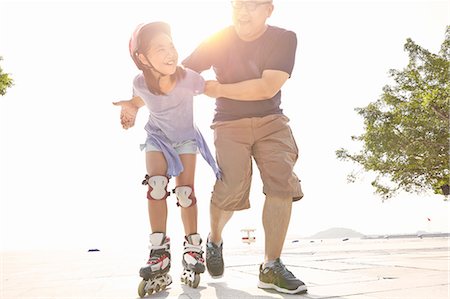 roller skating pictures - Mature man supporting daughter rollerblading at beach, Zhuhai, Guangdong, China Stock Photo - Premium Royalty-Free, Code: 649-08307176