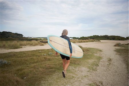 simsearch:614-08030822,k - Senior woman walking along beach, carrying surfboard, rear view Stock Photo - Premium Royalty-Free, Code: 649-08307261