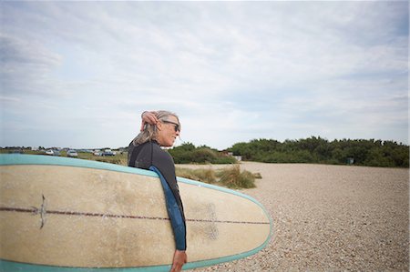 simsearch:614-08030822,k - Senior woman walking along beach, carrying surfboard, rear view Stock Photo - Premium Royalty-Free, Code: 649-08307262
