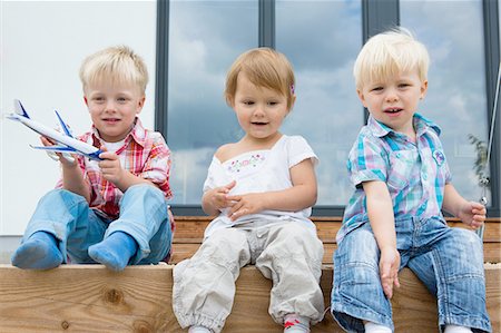 simsearch:614-07806393,k - Boy with toy airplane and two toddlers sitting on patio Stock Photo - Premium Royalty-Free, Code: 649-08307415