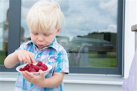 raspberry - Male toddler on patio eating a bowl of raspberries Stock Photo - Premium Royalty-Free, Code: 649-08307410