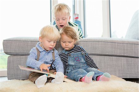 simsearch:614-06896931,k - Boy and two toddlers reading childrens book on living room floor Photographie de stock - Premium Libres de Droits, Code: 649-08307444