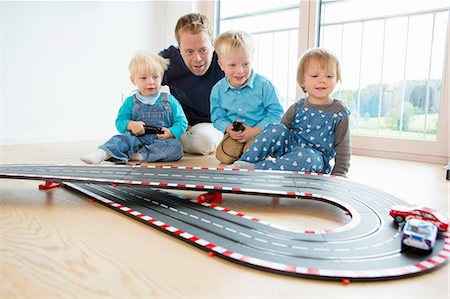 simsearch:649-07064267,k - Mid adult man and three young children playing with toy  racing cars on living room floor Stock Photo - Premium Royalty-Free, Code: 649-08307469