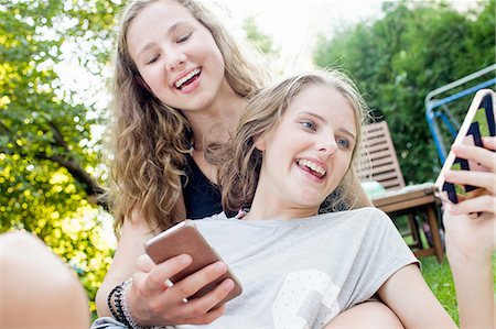 simsearch:649-07804673,k - Two teenage girls reading smartphone texts in garden Photographie de stock - Premium Libres de Droits, Code: 649-08307529