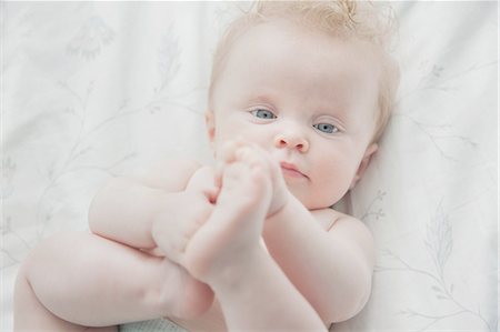 Baby girl, lying on back, holding feet Stock Photo - Premium Royalty-Free, Code: 649-08327700