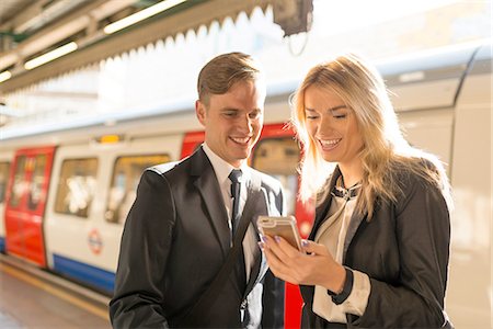 Businessman and businesswoman texting on platform, Underground station, London, UK Stock Photo - Premium Royalty-Free, Code: 649-08327770