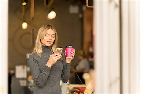 Woman with takeaway coffee using smartphone Stock Photo - Premium Royalty-Free, Code: 649-08327782