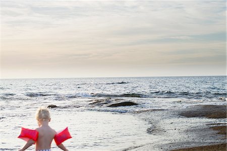 Rear view of female toddler wearing inflatable armbands at coast, Calvi, Corsica, France Stock Photo - Premium Royalty-Free, Code: 649-08328720