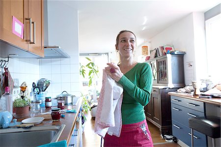 Mid adult woman in kitchen drying hands on tea towel looking away smiling Stock Photo - Premium Royalty-Free, Code: 649-08328792