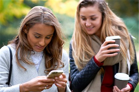 Two young female friends reading smartphone texts in park Stock Photo - Premium Royalty-Free, Code: 649-08328950