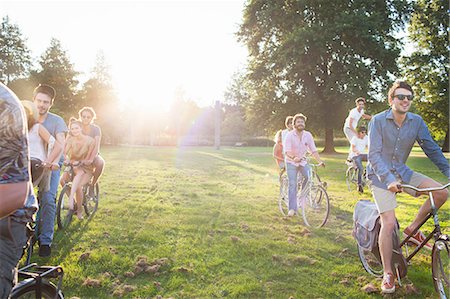 simsearch:649-08381087,k - Rows of party going adults arriving in park on bicycles at sunset Foto de stock - Sin royalties Premium, Código: 649-08381072