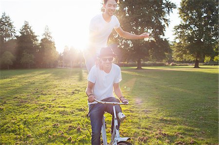 simsearch:649-08381087,k - Party going man arriving in park standing on back of bicycle at sunset Foto de stock - Sin royalties Premium, Código: 649-08381073