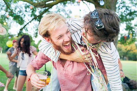 Two male adult friends wrapped in streamers hugging at sunset party in park Stock Photo - Premium Royalty-Free, Code: 649-08381093